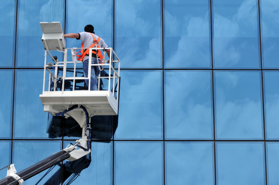 Worker cleaning the glass building